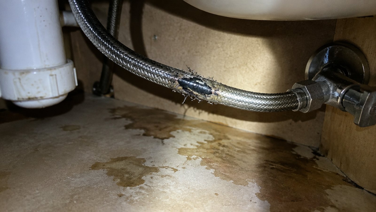 Failed braided flexible hose under a bathroom vanity, still connected